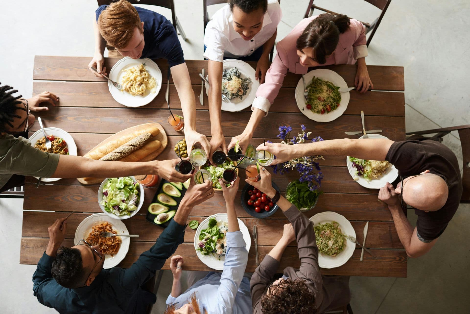 A group of friends laughing and sharing food at a restaurant table